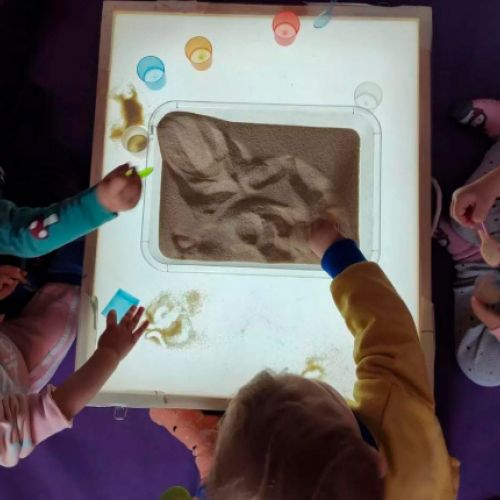 Niños manipulando arena seca en un recipiente